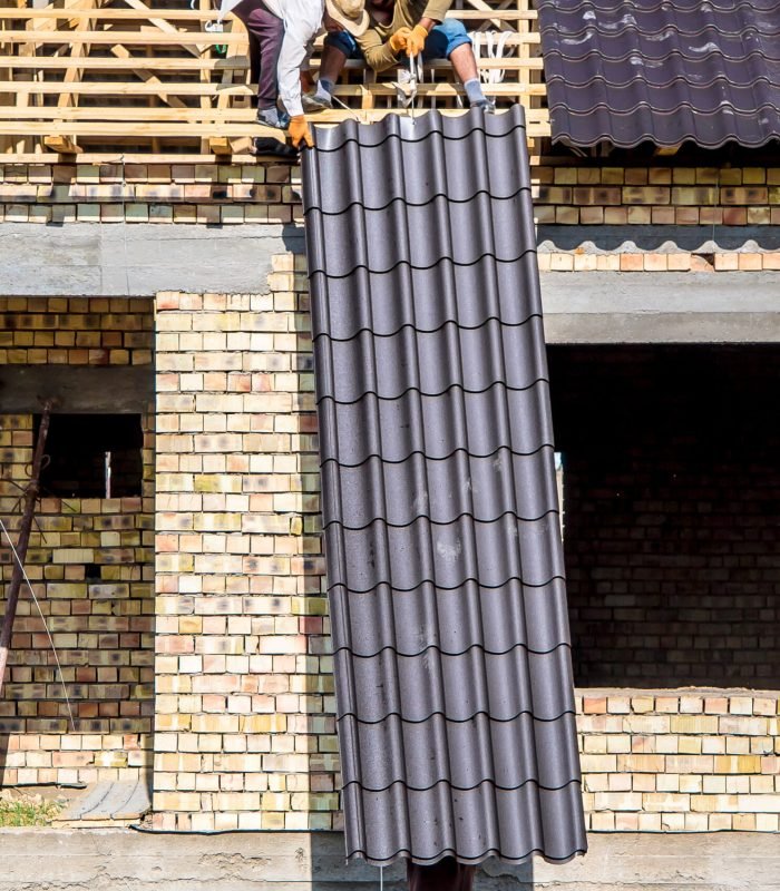 A man carries a metal profile on a construction site